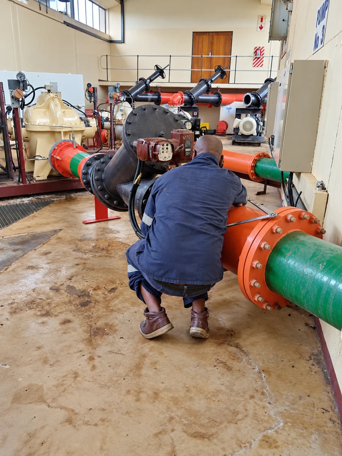 Technician working on an actuated valve on pump station pipework